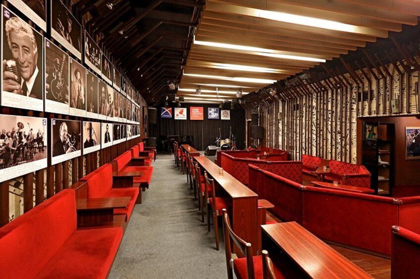 En restaurang med röda sittplatser och en vägg full av inramade fotografier. 5