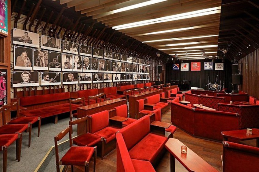 Un intérieur rouge et en bois, avec plusieurs espaces de détente et un mur recouvert de photographies encadrées. 4