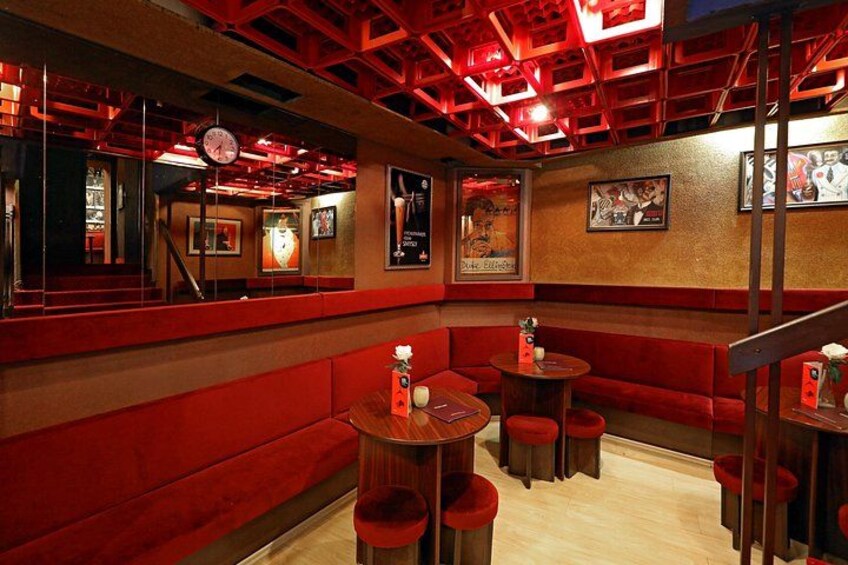 L’intérieur d’un restaurant à la décoration rouge, avec des banquettes, des tables et une horloge au mur. 3