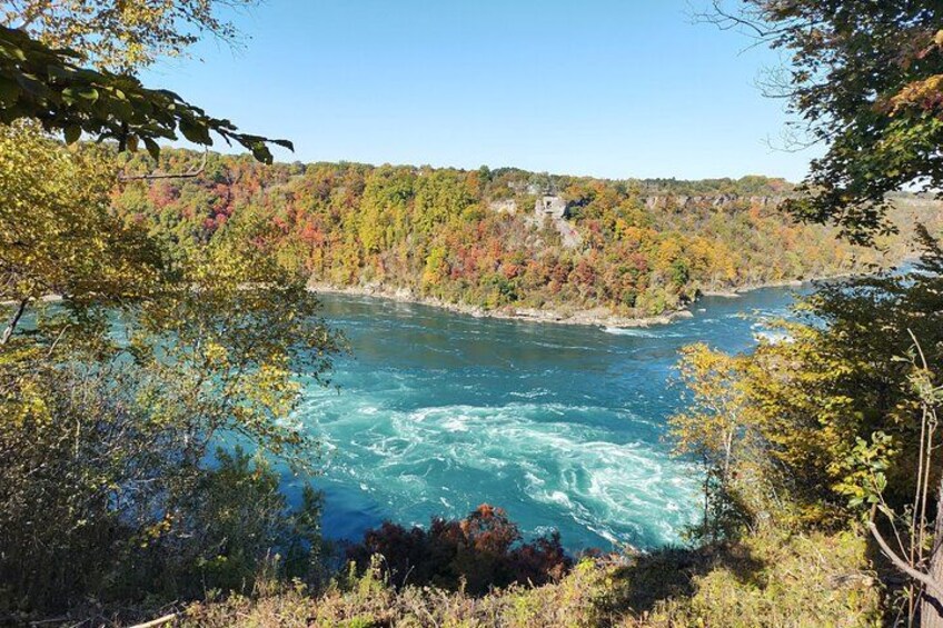 A river with white water rapids surrounded by autumn-colored trees. 4