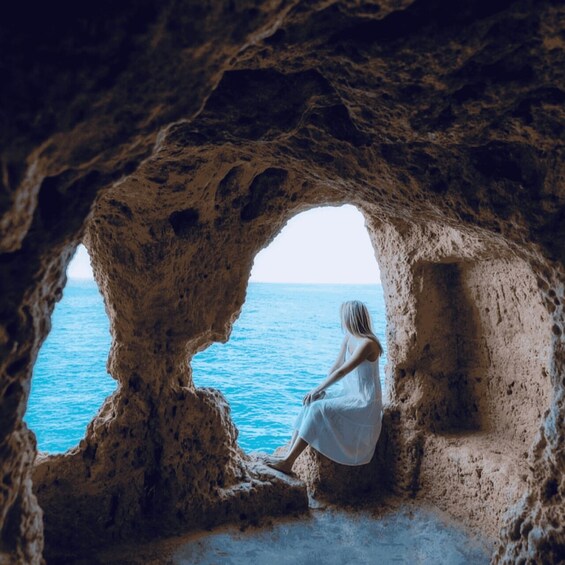 A person sitting inside a cave by the sea. 1