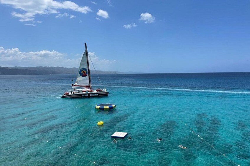 A sailboat on turquoise water, a clear sky, and distant mountains. 5