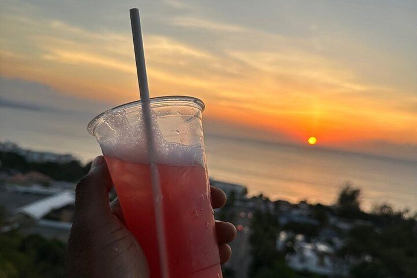 A sunset over the ocean with a hand holding a drink. 4