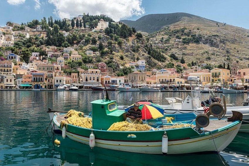 Un pueblo costero con edificios coloridos, un bote con equipo de pesca y aguas tranquilas. 4