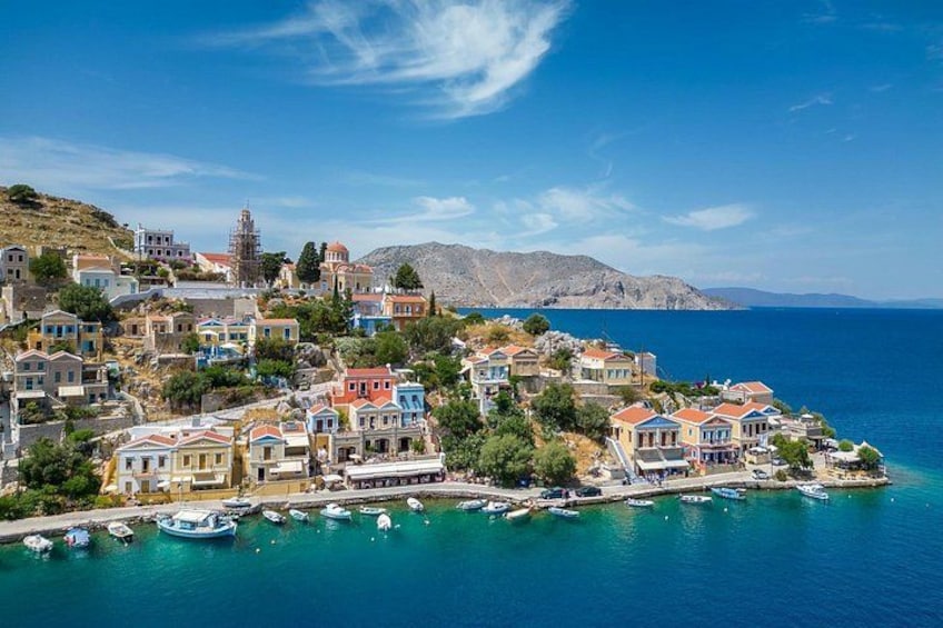 Un pueblo costero con casas coloridas, un mar azul cristalino y barcos amarrados a la orilla. 5
