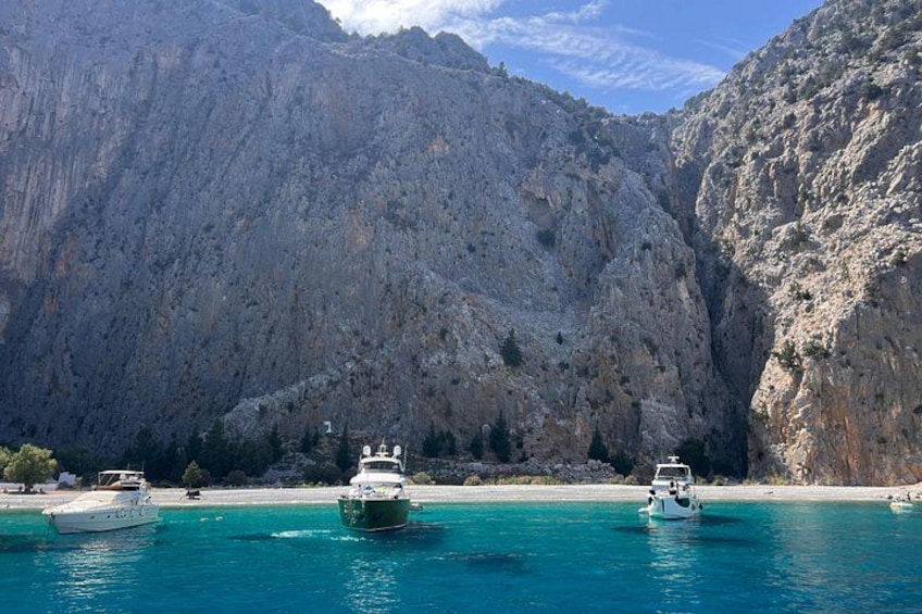 Escena costera con barcos sobre aguas turquesas, acantilados rocosos y cielo despejado. 2