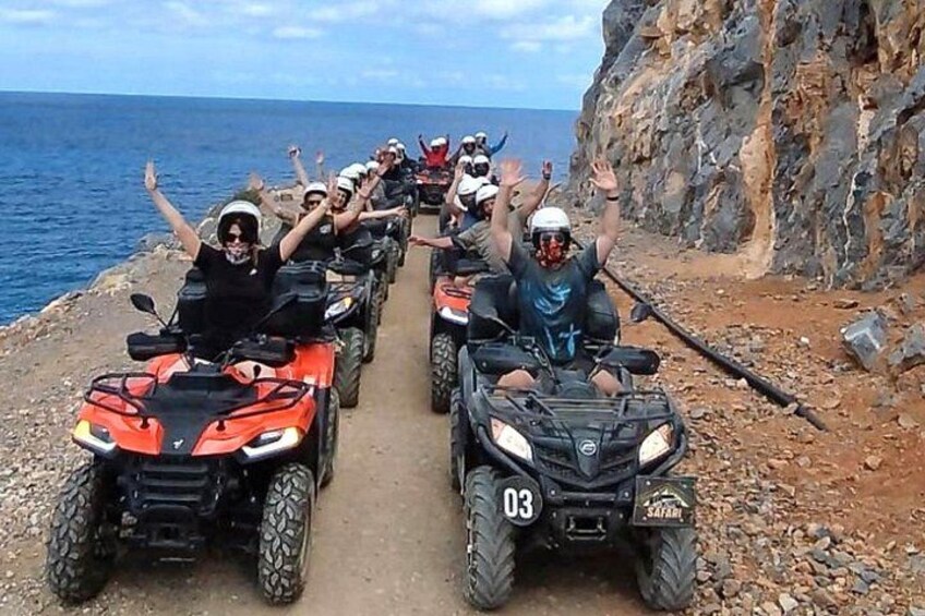 Un gruppo di persone su veicoli ATV su un sentiero roccioso vicino al mare. 1