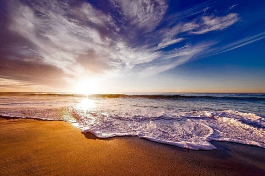 Una playa con olas, una puesta de sol y cielo despejado. 2