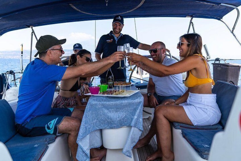 Een groep mensen op een boot, die met drankjes proosten, met een gedekte tafel voor een maaltijd. 2