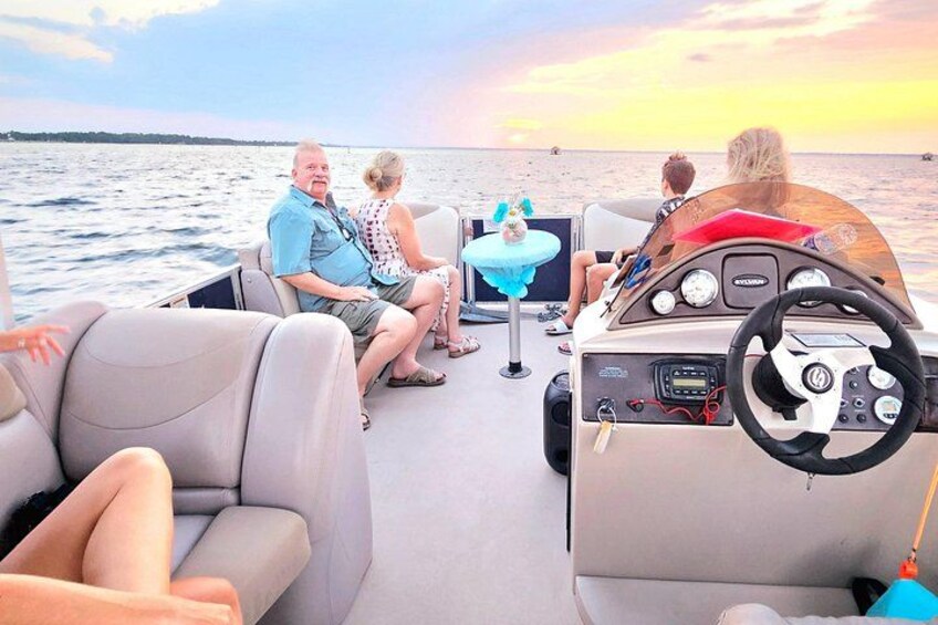 A boat with people on deck, a steering wheel, and a table with a drink. 4
