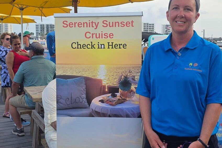 A person standing in front of a Serenity Sunset Cruise advertisement. 2