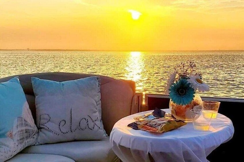 A sunset over the ocean with a table set for two, featuring a vase with flowers and a drink. 3
