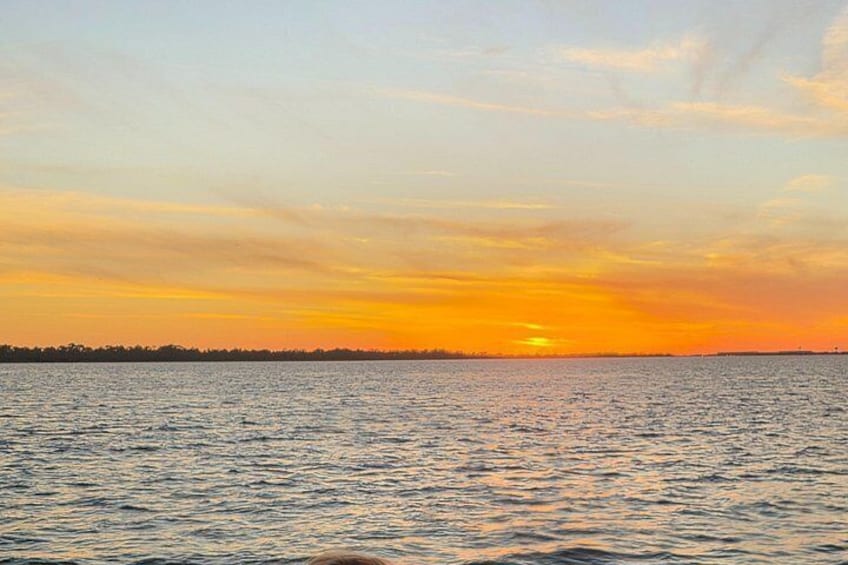 A sunset over a body of water with a distant shoreline. 2