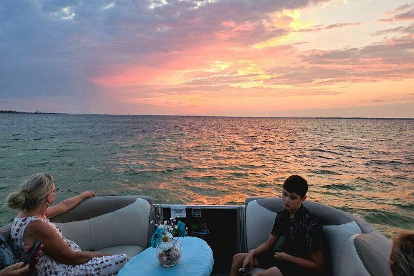 A sunset over water with a boat and people on it. 3