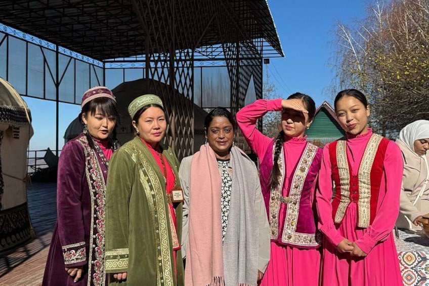 A group of people in traditional attire standing in front of a building with a distinctive roof structure. 1