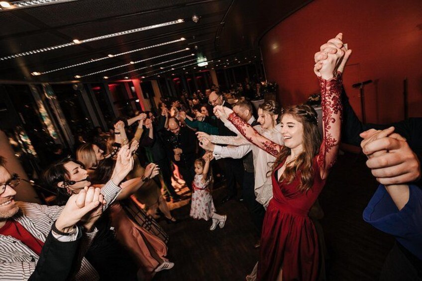 Un grupo de personas bailando en una sala tenuemente iluminada con una pared roja. 5