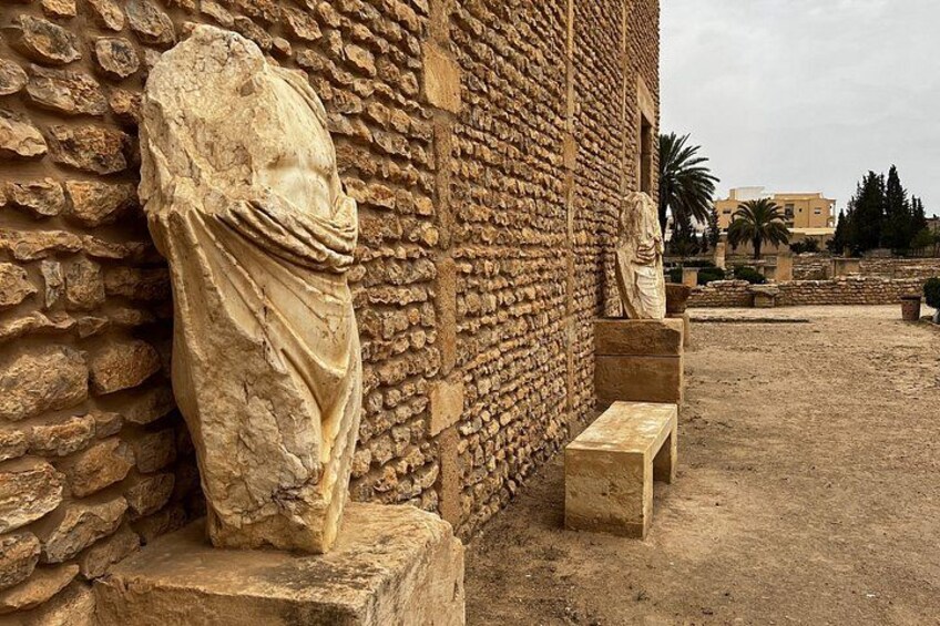 A stone statue, a stone bench, and a stone wall with a rough texture. 4