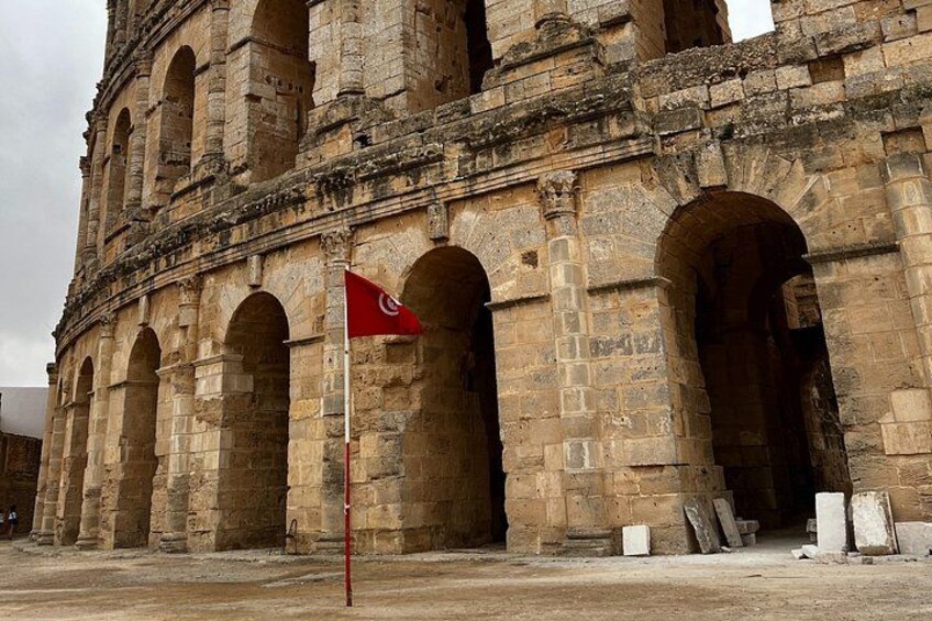 A historic stone building with arches and a red flag. 2