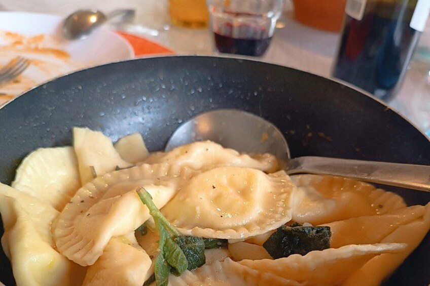 A bowl of ravioli with vegetables and sauce. 4