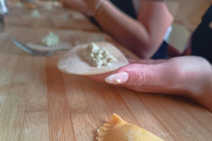 A person holding a piece of food on a wooden table. 2