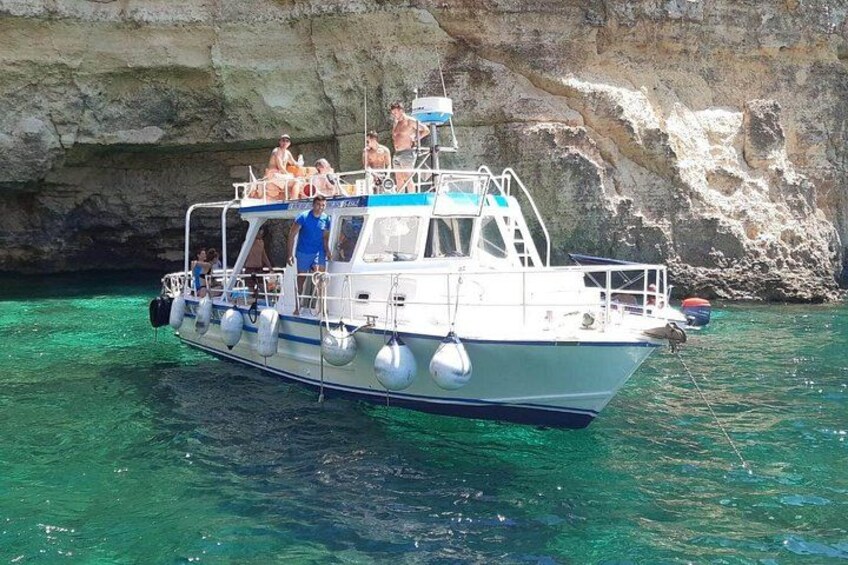 Un bateau transportant des passagers, une eau turquoise et limpide, et une falaise rocheuse en arrière-plan. 4