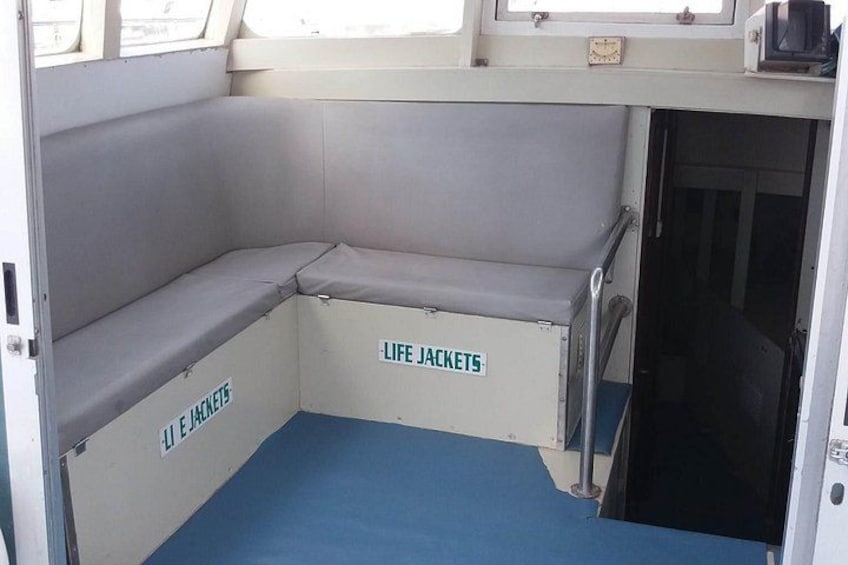 L'intérieur d'un bateau, avec des gilets de sauvetage accrochés aux murs et un plancher bleu. 3
