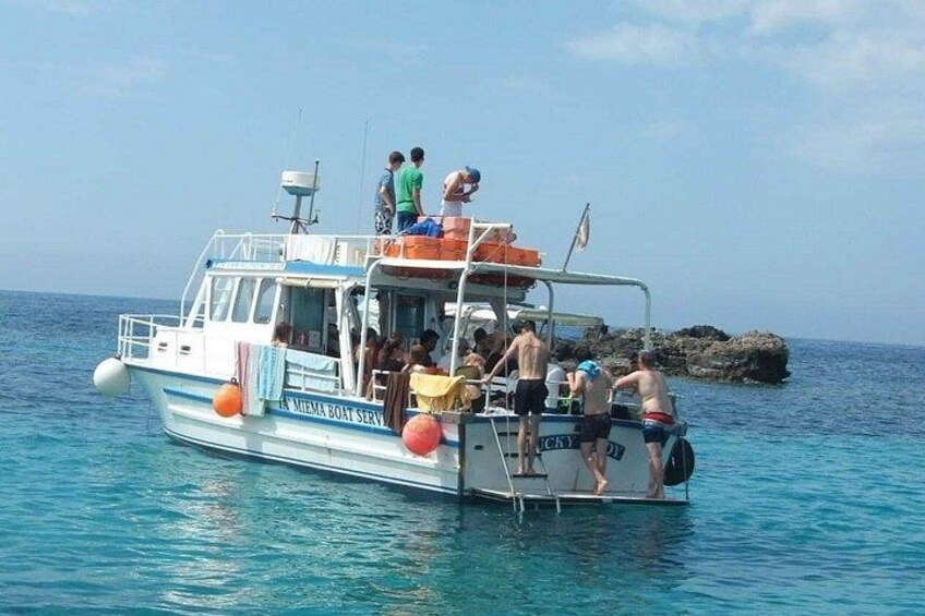 Un bateau où des personnes montent et descendent, entouré d’eaux bleues et calmes et d’une côte rocheuse. 2