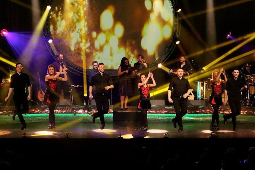 A group of people performing on a stage with musical instruments and a large screen in the background. 3