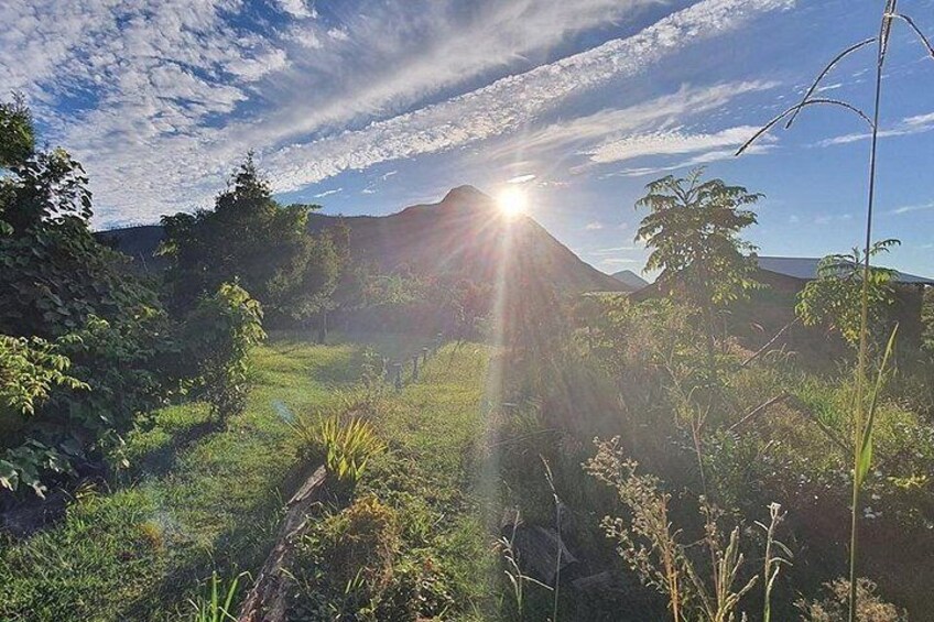A landscape with a sunlit mountain, greenery, and a clear sky. 3