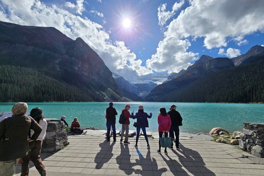 Un groupe de personnes se trouve sur une jetée, d’où l’on peut admirer un lac turquoise avec des montagnes en arrière-plan. 2