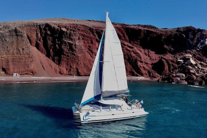 En segelbåt på stilla vatten med en klippig kustlinje i bakgrunden. 3