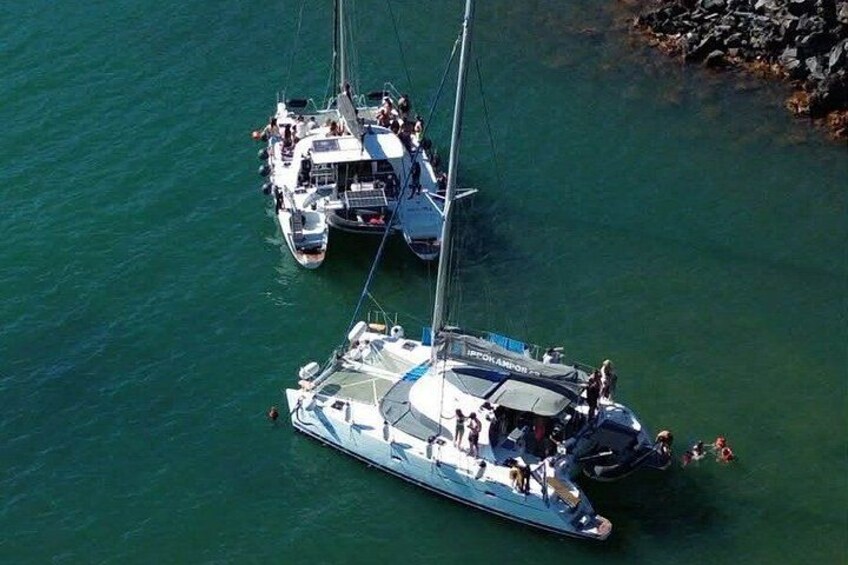 Un velero amarrado cerca de una costa rocosa, con otra embarcación al fondo. 2
