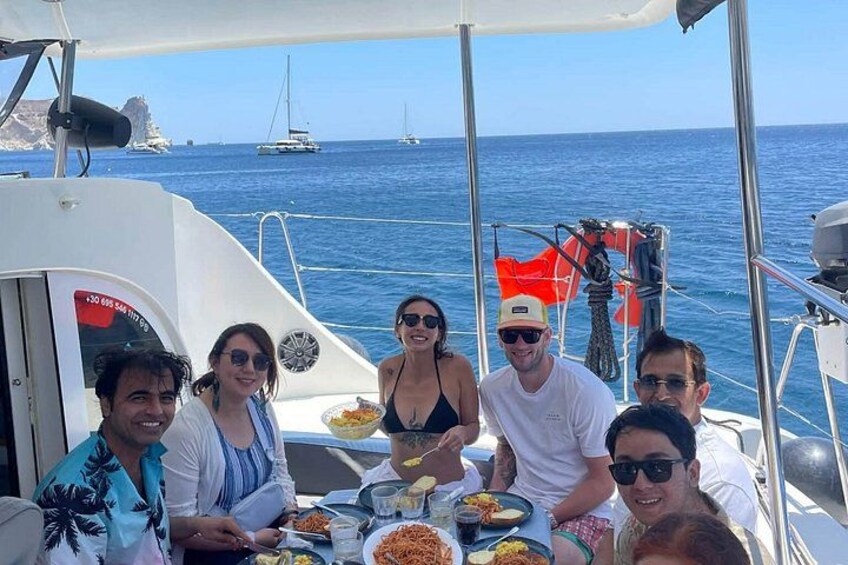 Un grupo de personas cenando en un barco, con el mar y otras embarcaciones al fondo. 5