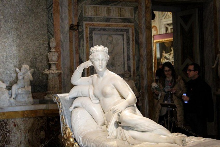 A classical statue of a reclining woman in a museum. 2