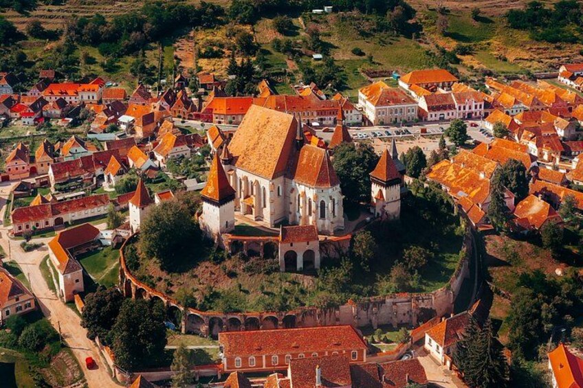 A historic town with red-roofed buildings, a prominent church, and a fortified wall. 5