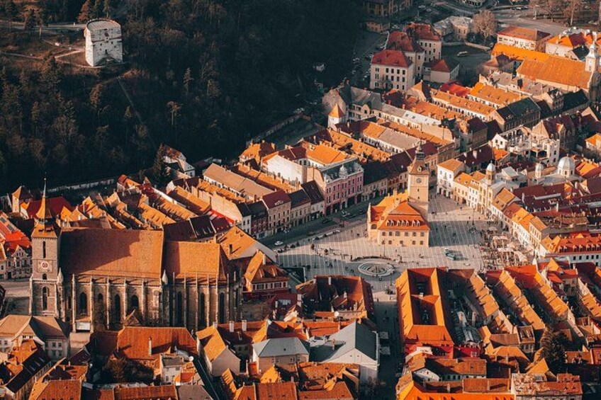 En historisk stad med röda tak på byggnaderna, ett centralt torg och en framträdande kyrka. 3