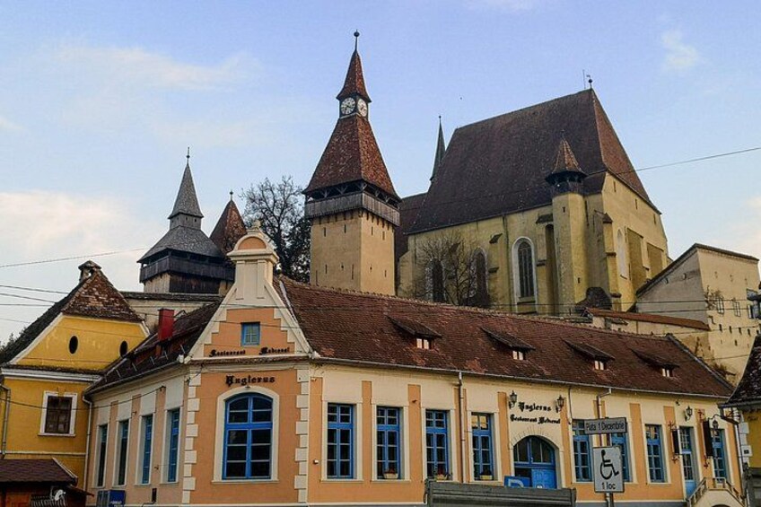 A historic building with a clock tower, a restaurant, and a sign for a local business. 2
