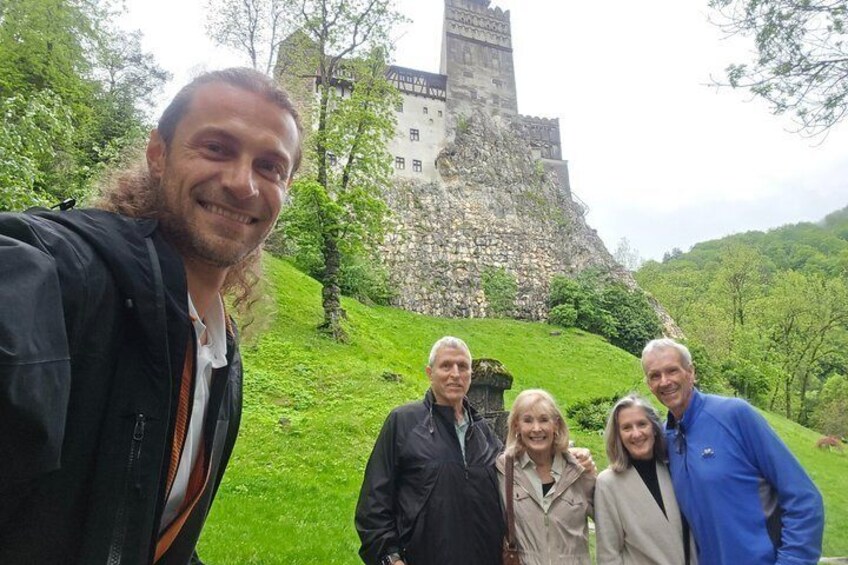 A group of people standing in front of a castle on a grassy hill. 2