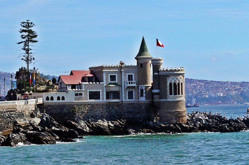 A coastal castle with a red roof, a flag, and a rocky shoreline. 3