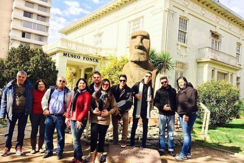 A group of people standing in front of a building labeled 'MUSEO FONCK' with a large stone statue of a man's head in the center. 5