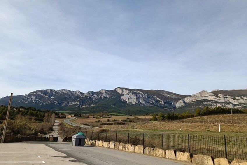 Une route asphaltée bordée d’une clôture métallique, une petite construction et, au loin, un paysage montagneux. 5