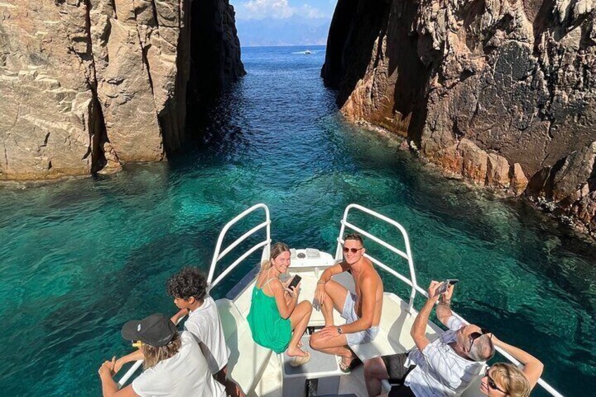 A boat with people enjoying the clear blue water and rocky cliffs. 5