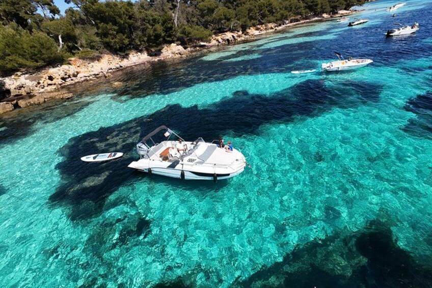A clear turquoise sea with boats anchored near the shore. 1