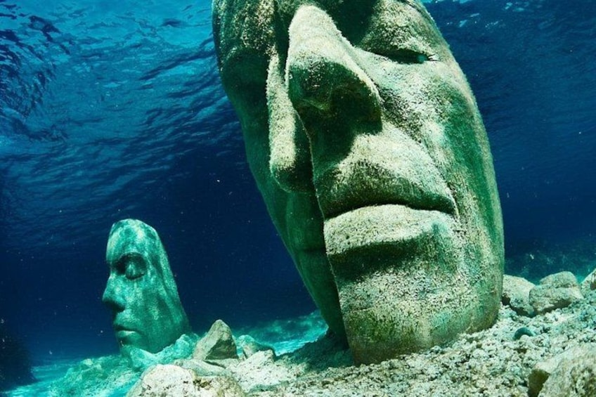 A large stone face underwater, surrounded by smaller rocks and marine life. 4