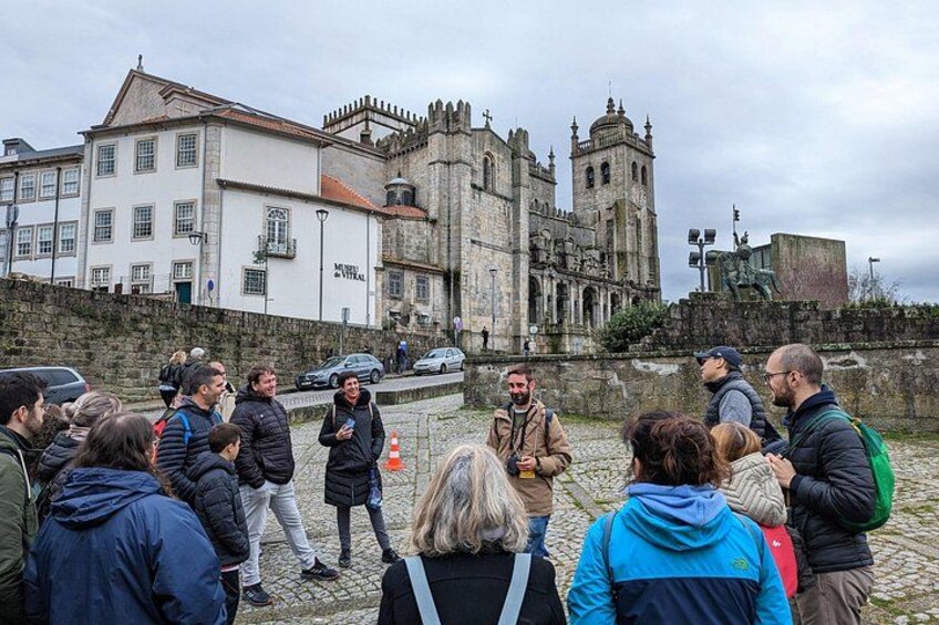 Un grupo de personas reunidas frente a un edificio histórico con una torre alta y una estatua. 3