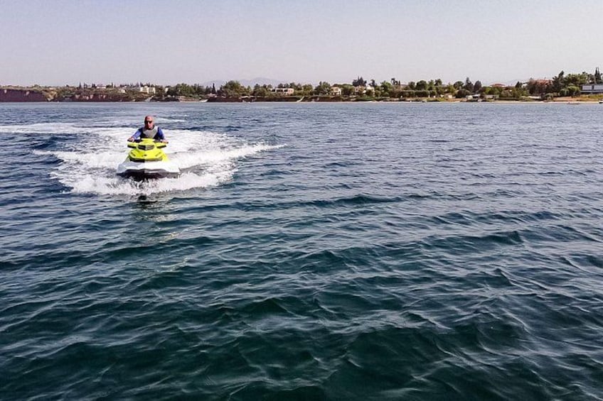A person riding a yellow jet ski on a body of water with a shoreline in the background. 3