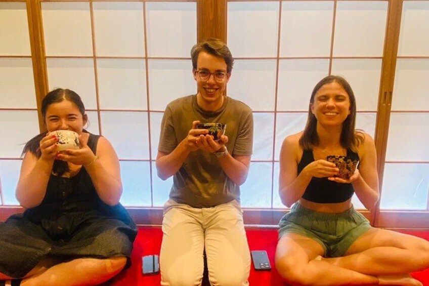 Three people sitting on a red bench with a wooden backdrop. 3