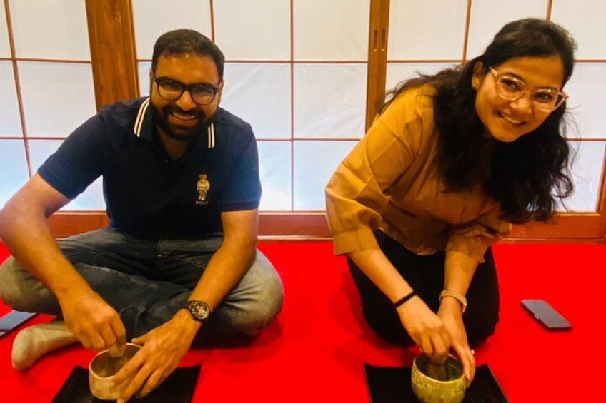 Two people sitting on a red floor, each holding a cup. 5