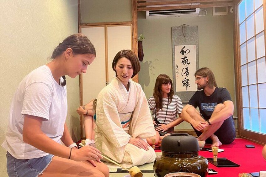 A group of people sitting around a table with a large jar in the center. 1