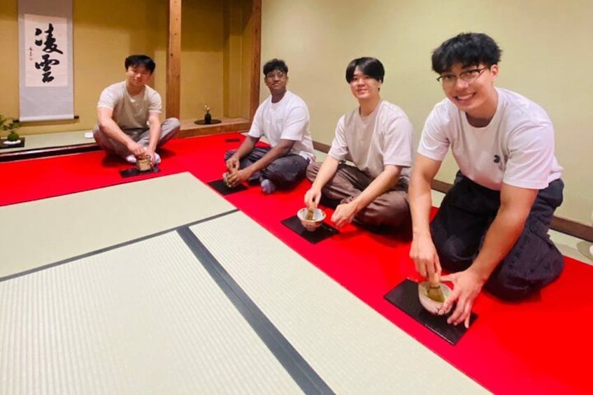 Fire personer sidder på stråmåtter i et traditionelt japansk rum. 3
